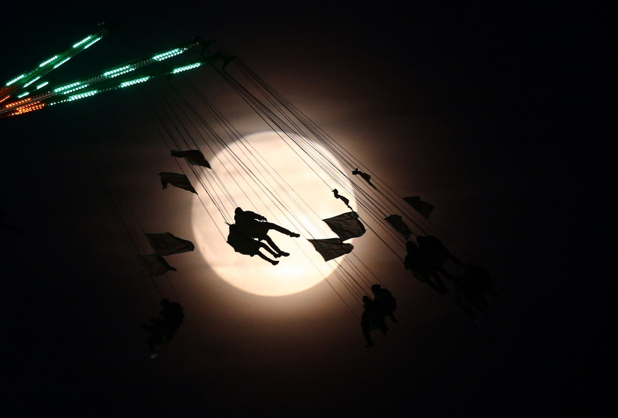 انگلستان، سایه رخ مردم در مقابل ماه در شهر بازی، یک روز پیش از ابر ماه، لندن، انگلستان. عکاس: نیل سالن / رویترز