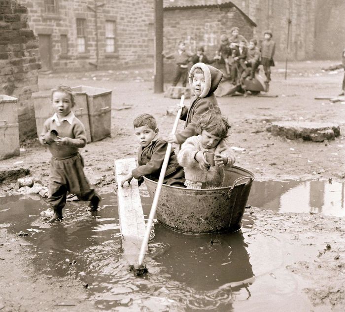بچه‌هایی در محله‌ای فقیر نشین از شهر گلاسگو، در حال قایق سواری هستند، اسکاتلند، دهه 1960